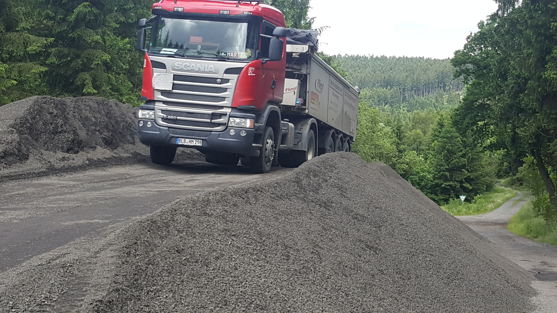 Scania-Kipper von Hackenbracht zwischen Schüttguthaufen auf einem Lagerplatz